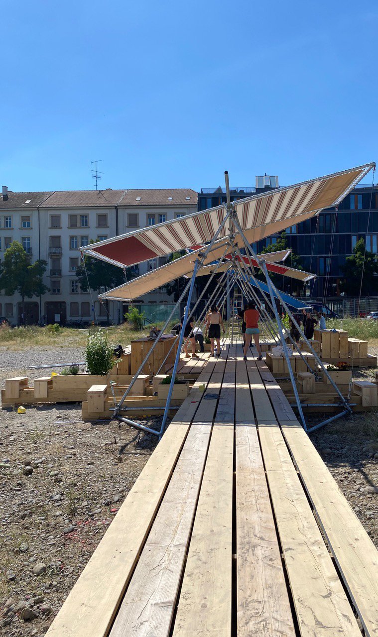 Holzplankenweg mit Sonnensegeln und städtischem Hintergrund