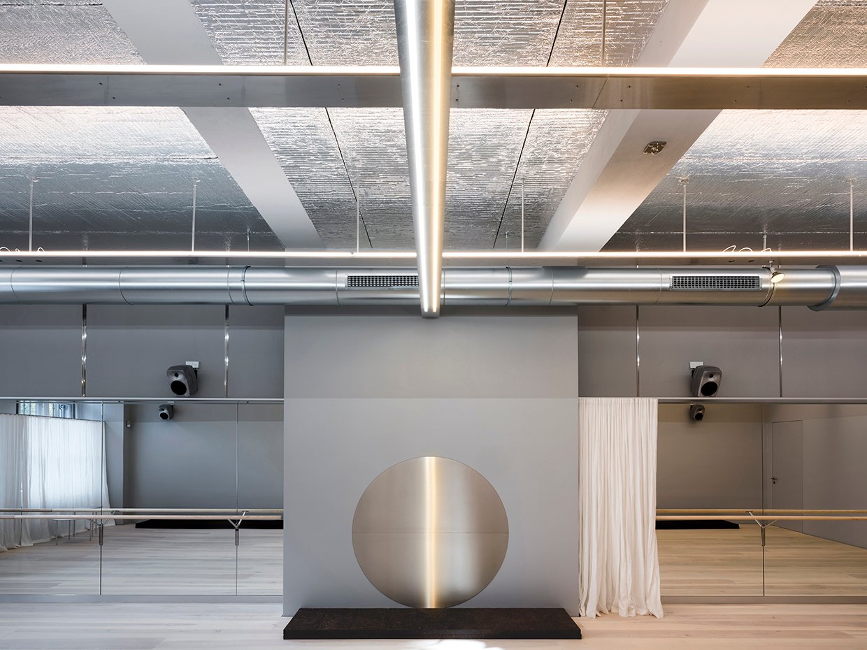 Modernes, minimalistisches Interieur mit industrieller Beleuchtung und einem runden Kunstobjekt an der Wand