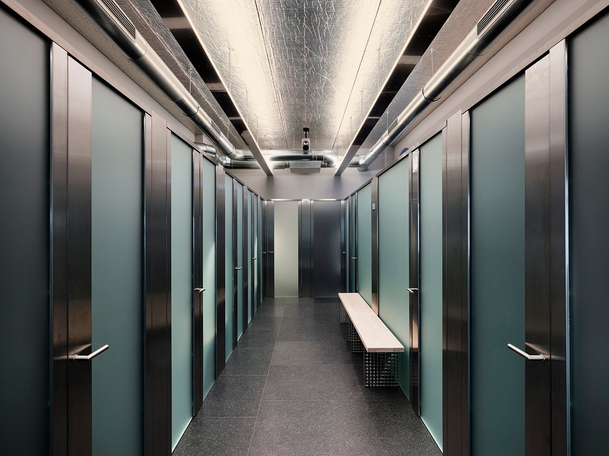 Modernes Büroflurdesign mit Reihen von Glas- und Metalltüren und einer langen, beleuchteten Decke