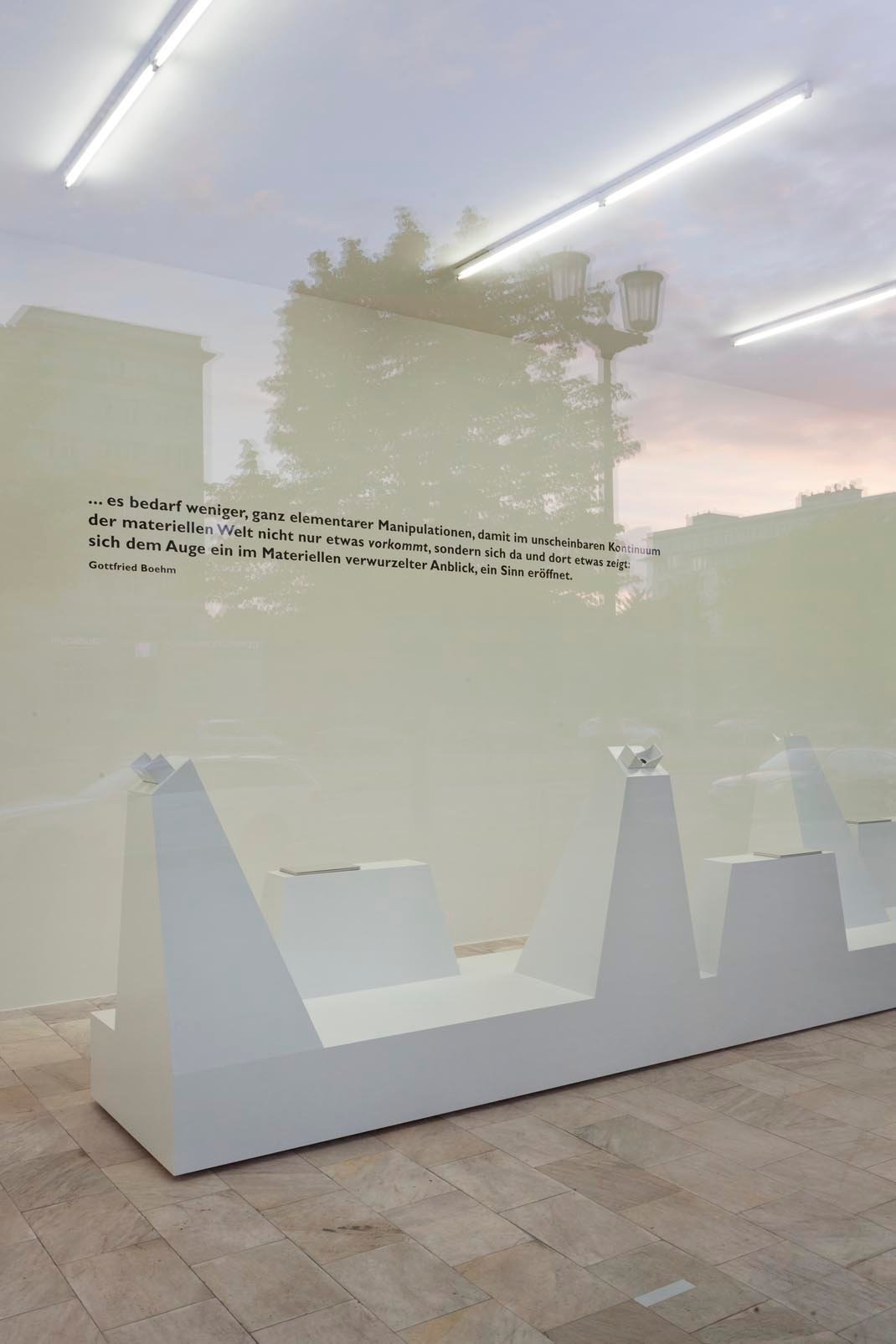 Moderne, minimalistische Kunstausstellung mit weißer Präsentation und Texttafeln an der Wand