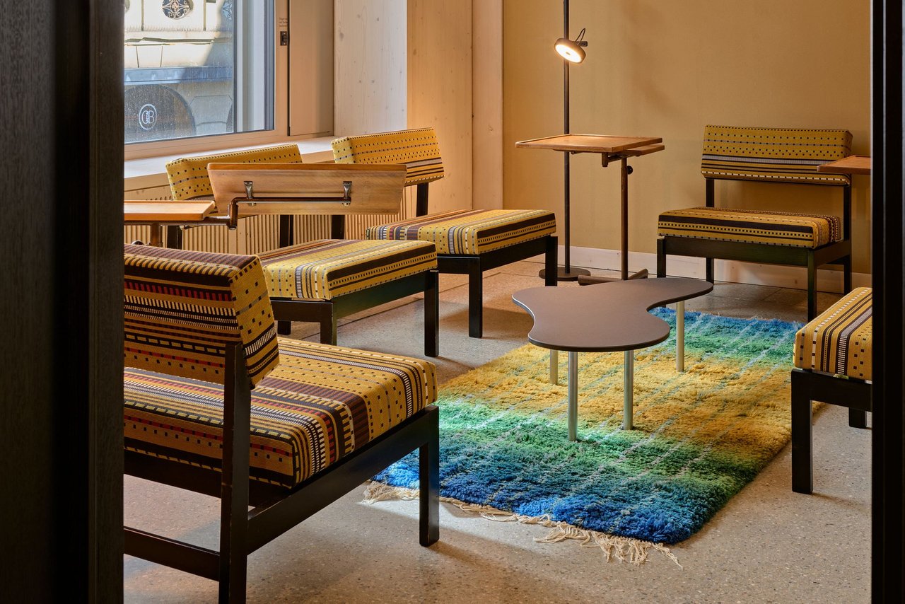 Ein modernes Wohnzimmer-Set mit gemusterten Sitzbänken, einem runden Couchtisch und einem Teppich in Blau- und Grüntönen.